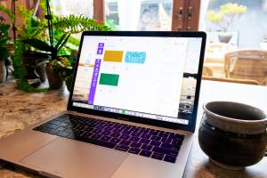 laptop sits on a desk beside a mug